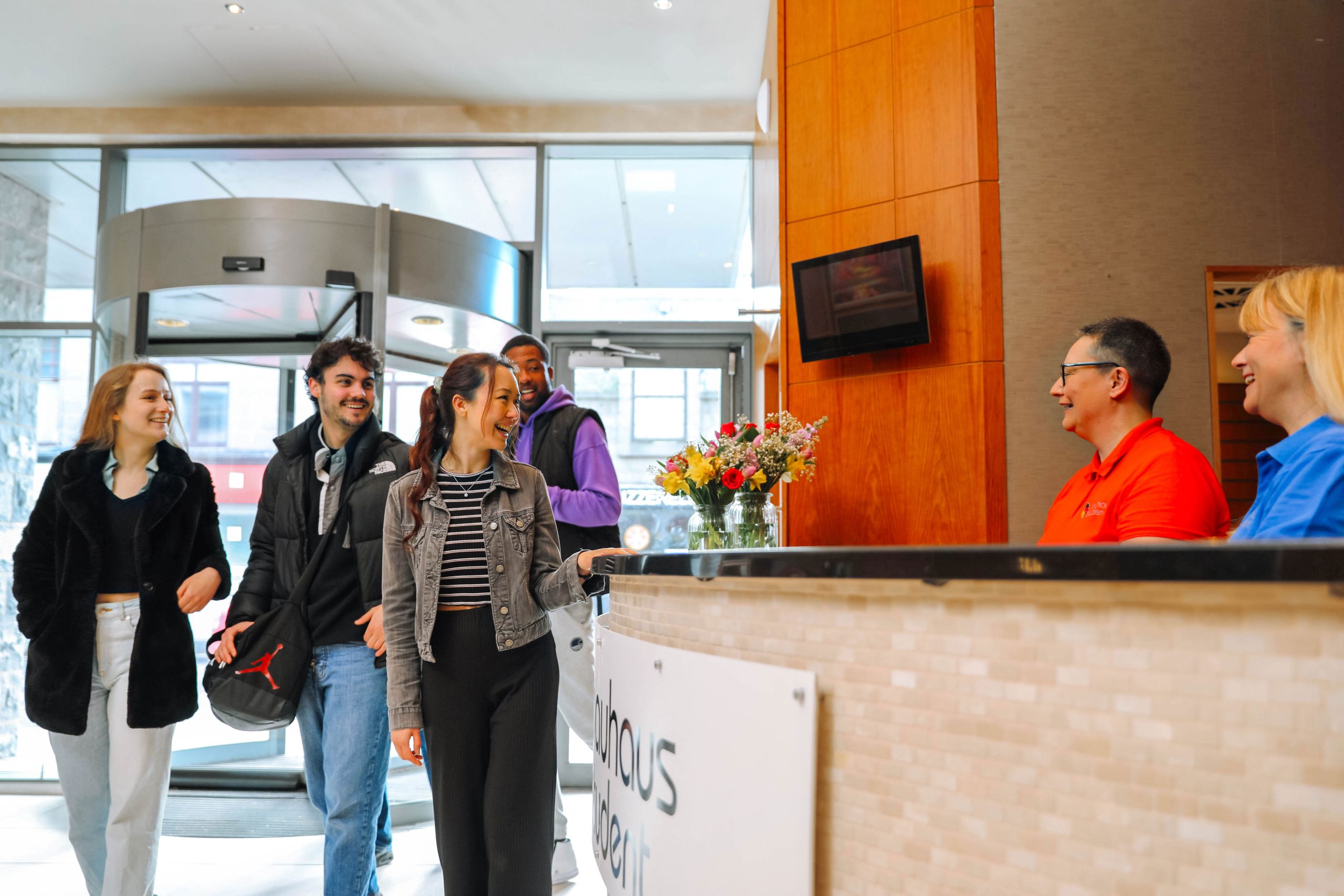 Receptionists welcoming a a group of students in the reception
