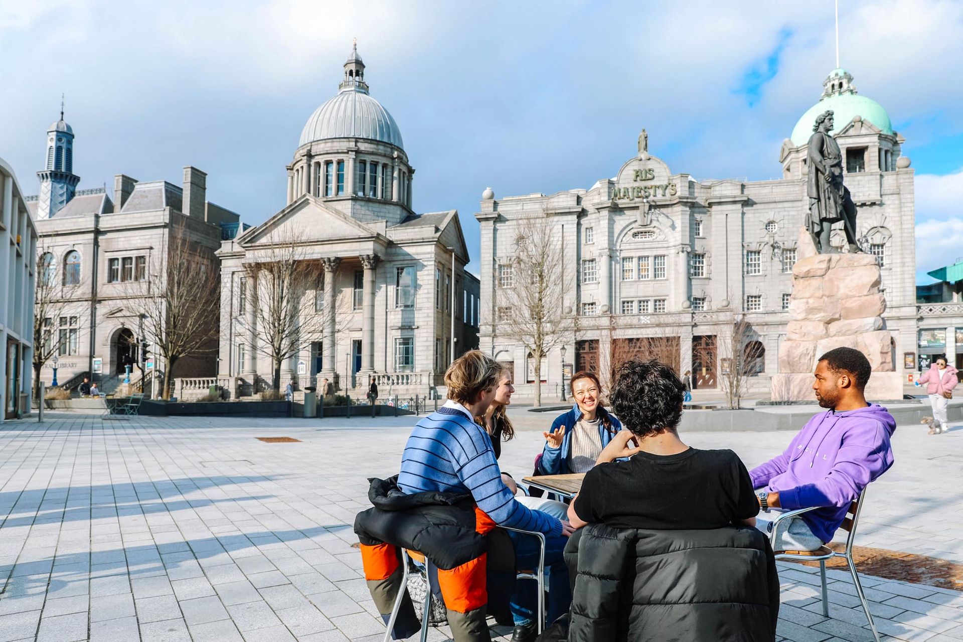 A group of students sitting in a Aberdeen city square close to their student accommodation